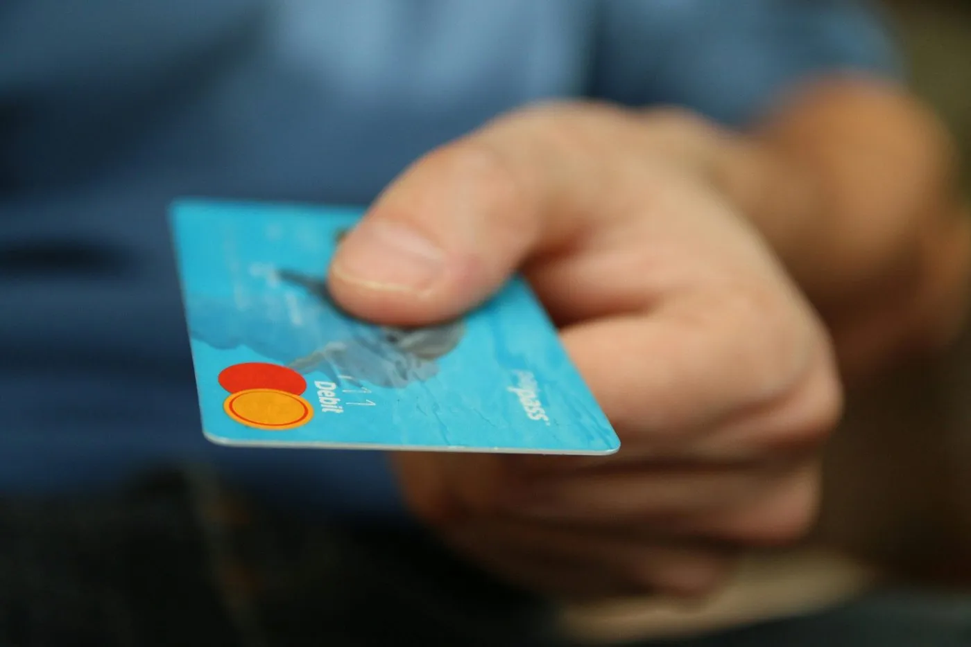 A hand offering a blue debit card, symbolising AI-driven conversions.