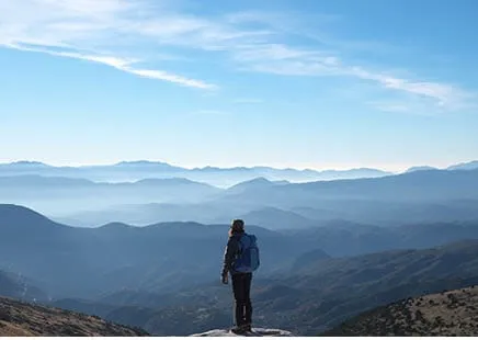 A person stands on a mountain peak, symbolizing growth and exploration, akin to a B2B SEO agency boosting startup visibility.