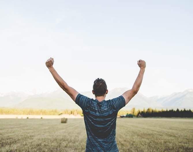 A person celebrates in a field, symbolising authority growth through link building.