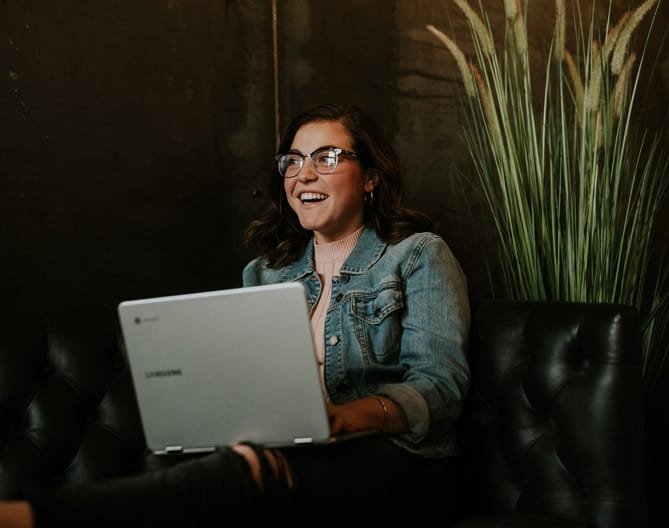 A smiling person using a laptop, symbolising SEO copywriting work.