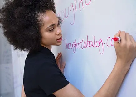 A woman writing on a whiteboard while planning a content strategy.