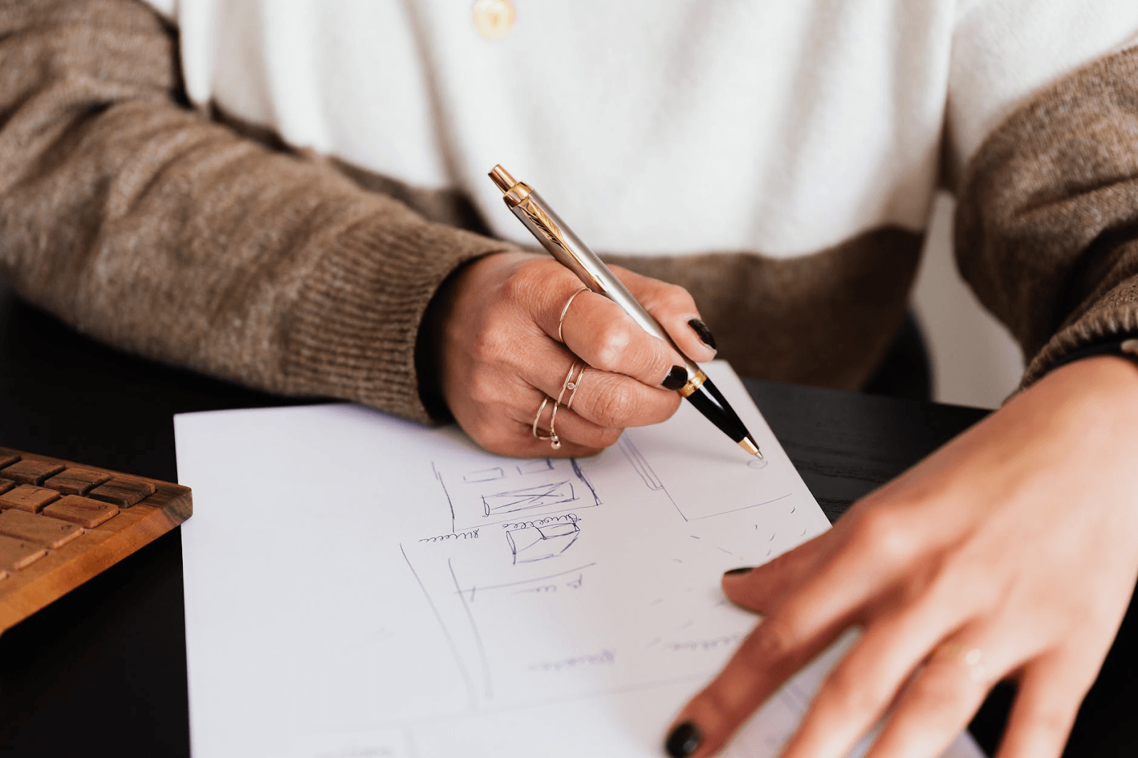 Hands sketching SEO strategies for startups, highlighting services by a B2B SaaS SEO agency and AI SEO company on paper.