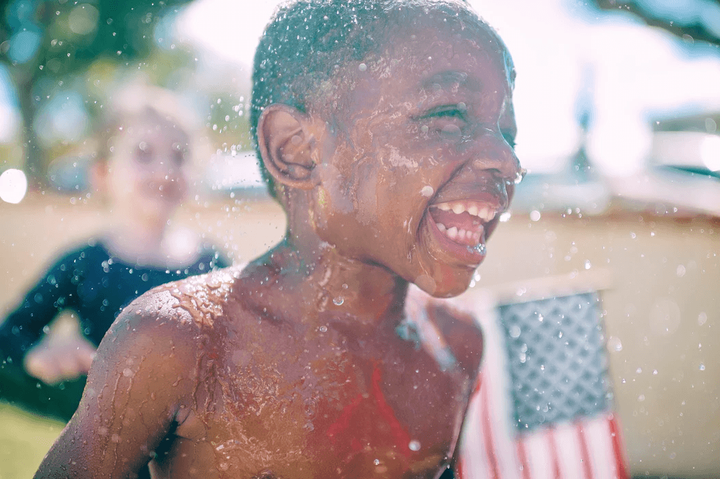 A child joyfully plays in water, capturing the essence of summer fun and carefree moments.