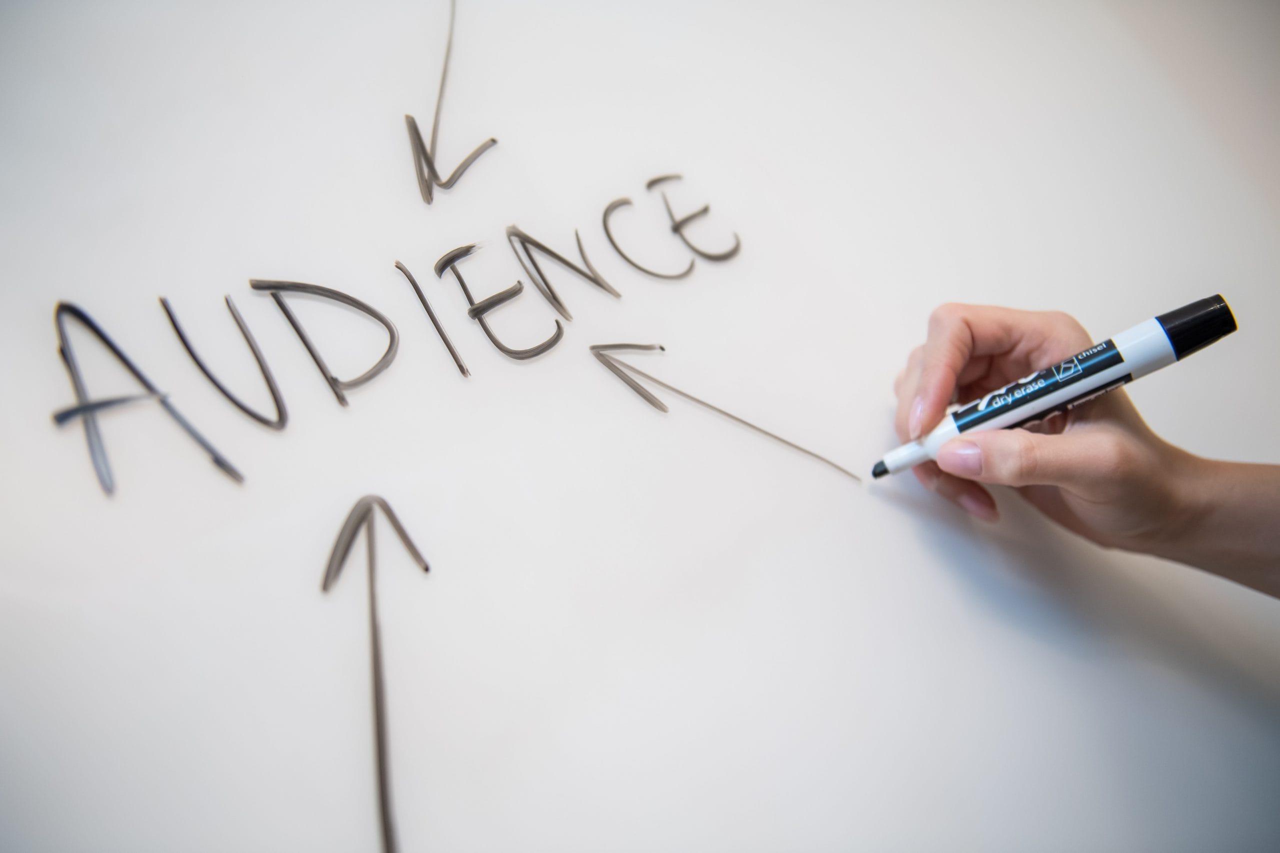 Hand writes "AUDIENCE" on whiteboard, highlighting focus of SEO agency for startups, AI SEO, and B2B SaaS SEO services.